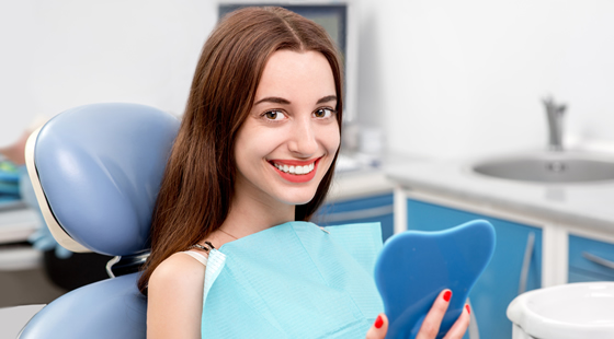 A woman in a dentist chair looking at her perfect teeth in the mirror Marietta GA